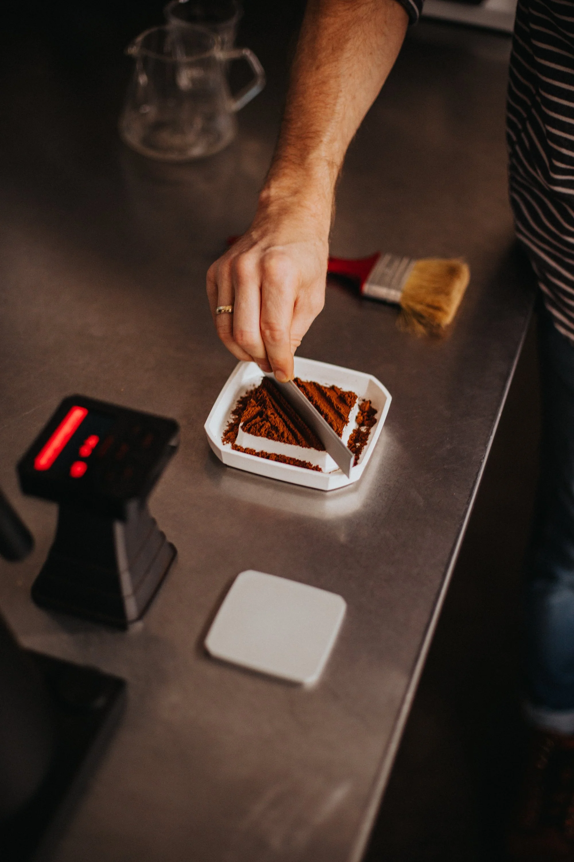 Chocolate being measured in a container, with coffee preparation tools in the background.